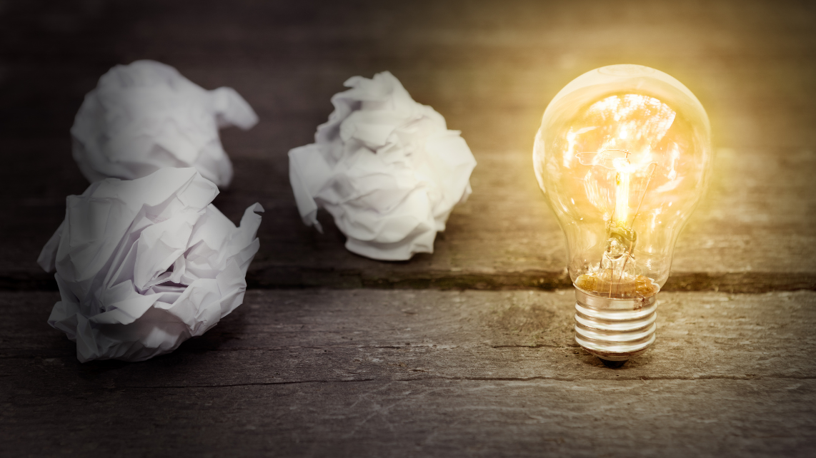 An image of two crumpled papers beside the glowing light bulb at the right-hand side