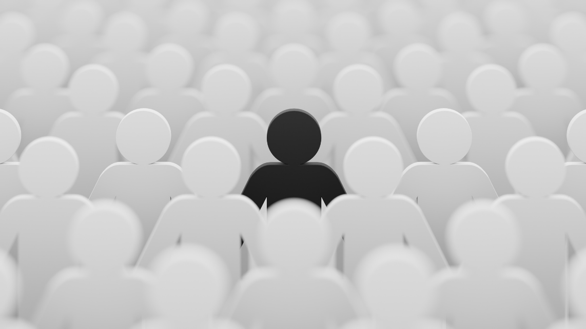 A black color figurine among crowd of white color ones