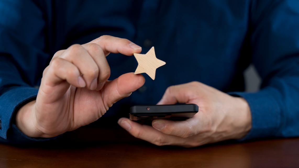 A man using his phone while holding a 1 star, symbolizing poor customer experience