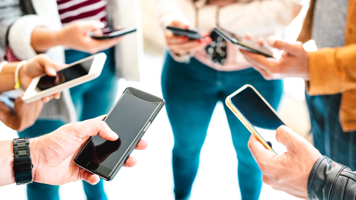 A group of friends sharing content on smartphones. Close up shot of mobile phones and hands.